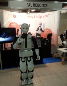 The biped humanoid robot REEM-C standing in front of PAL Robotics' desk at Humanoids Conference 2014