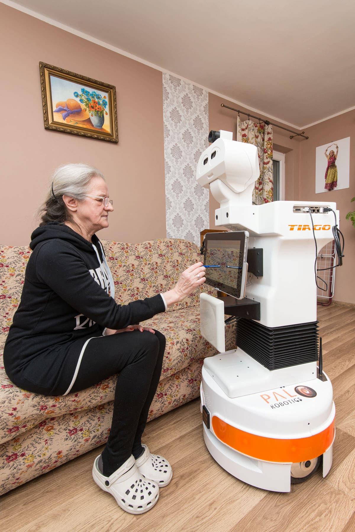Elderly woman interacts with the touchscreen of TIAGo robot