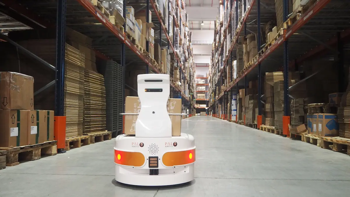 The autonomous mobile robot (AMR) TIAGo Base transporting a box in a warehouse
