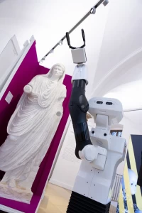 The mobile manipulator TIAGo robot in front of a statue