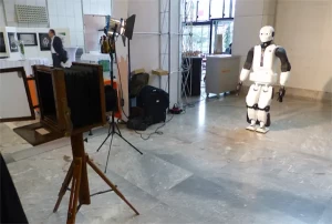 The biped robot REEM-C posing in front of an old camera